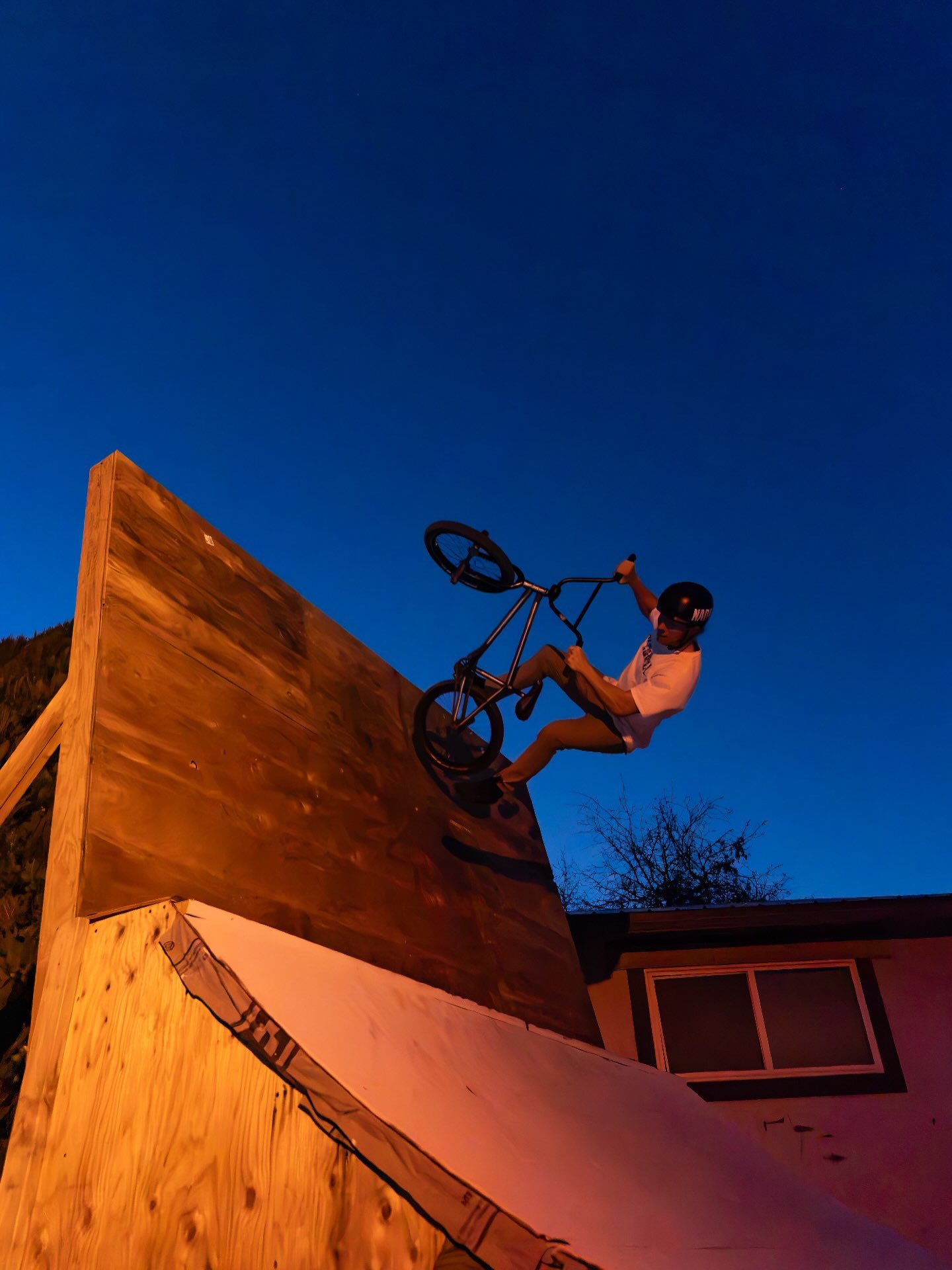 Melville Smith riding up a wooden wall ramp at dusk